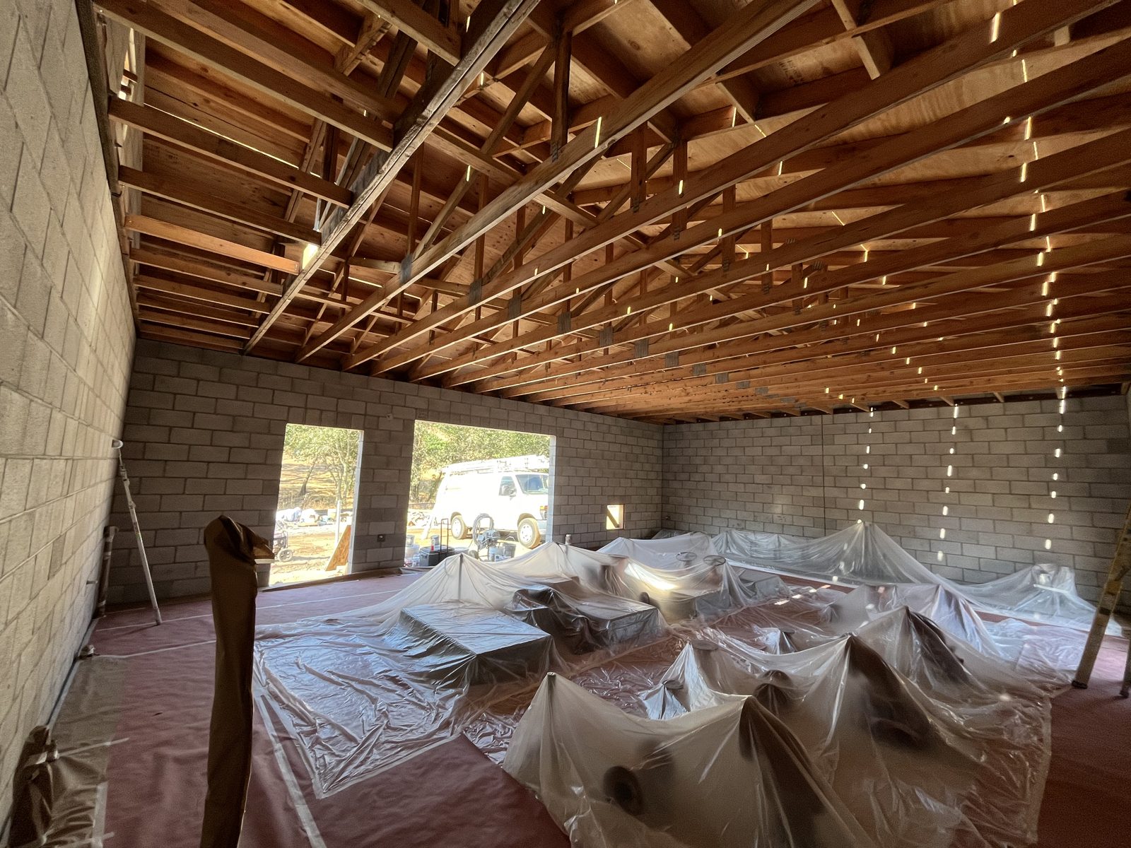 Room with a bare wood ceiling and block walls before painting