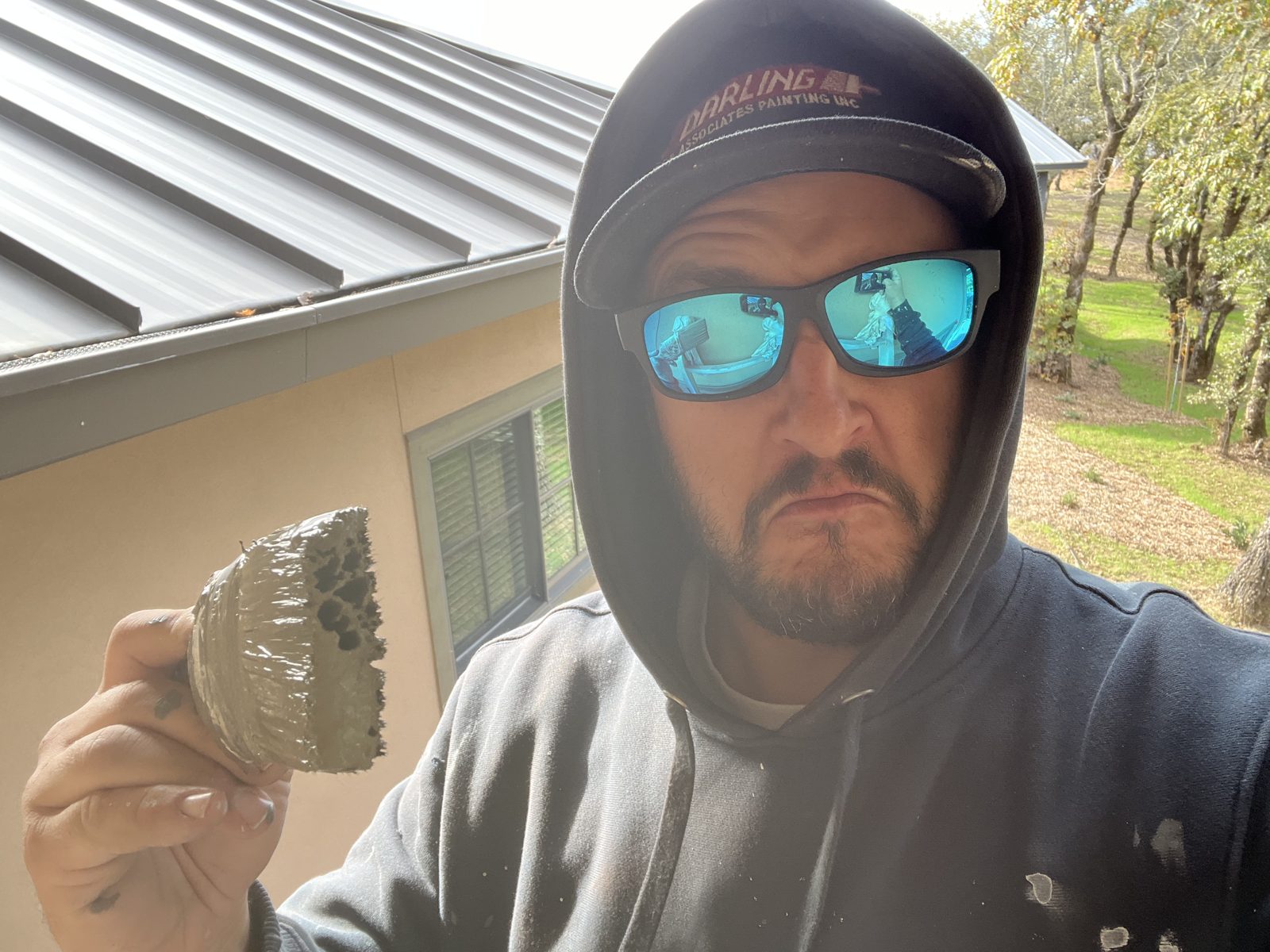 Frank holding a chunk of old material in front of a house exterior