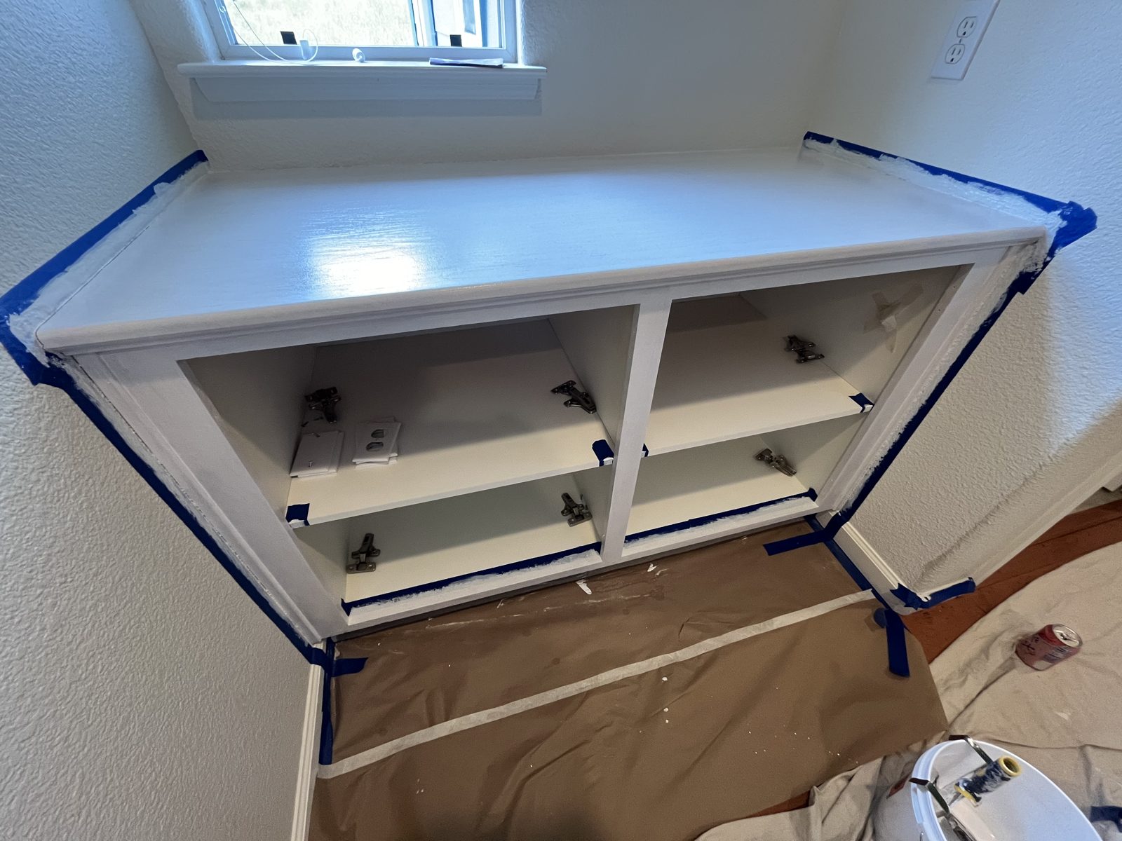White hall cabinet taped off before painting