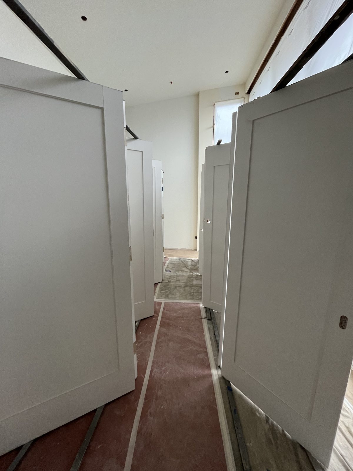 Rows of white doors standing on a rack in a room covered with protective paper