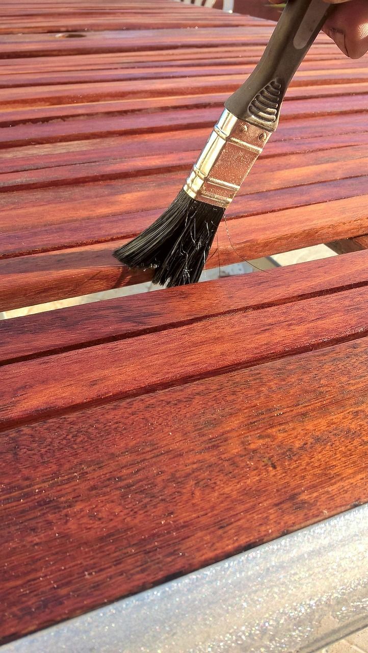 A brush applying wood stain to wooden slats